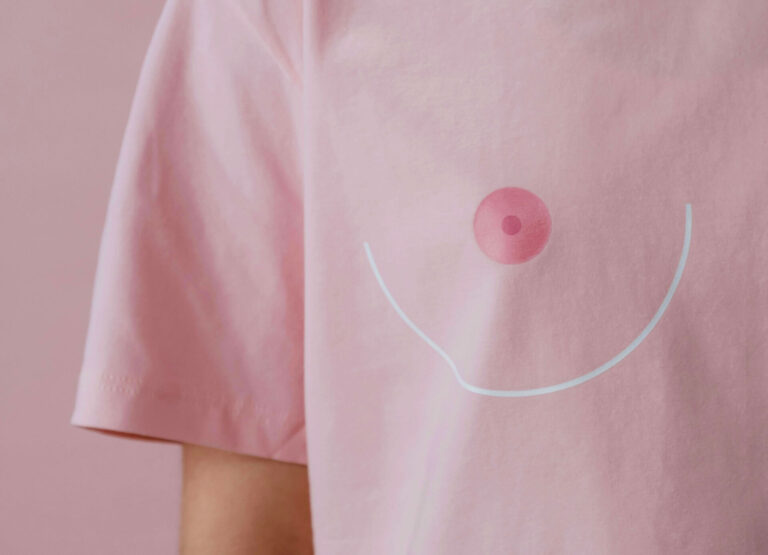 Person in pink T-shirt with a stylized breast illustration on the front.